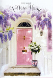 This photograph shows a Pimlico entrance that feels like a softly spoken celebration of a fresh chapter. The focal point is a pale pink front door, its colour tender and calming, framed by smooth whitewashed walls and a single, gently painted shutter that together create a clean, luminous backdrop. Draped above and to the sides of the door, wisteria pours down in generous cascades, each trailing stem heavy with clusters of lavender and lilac blooms. Their abundance forms a natural arch, like a curtain gently pulled back to reveal a new life inside, and you can almost sense the delicate perfume they release into the London air. On the doorstep, a grey metal bucket with a slightly worn finish rests securely against the threshold, filled to overflowing with plush white roses. These roses are creamy and full, their petals layered in soft spirals, surrounded by sprigs of muted green foliage that add depth and texture without disturbing the calm palette. A narrow pink ribbon has been tied snugly around the bucket, its pastel tone harmonising with the door and drawing the eye to the abundant blooms within. The light is warm but not harsh, filtering across the scene as if it were an early afternoon near St George's Square, casting slight shadows from the wisteria onto the steps and highlighting the contours of each rose petal. The overall feeling is one of quiet optimism and gentle welcome, the kind of thoughtfully arranged doorway flowers that make a new Pimlico address feel instantly cherished and truly home.